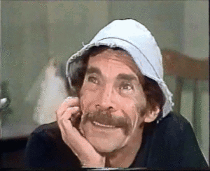 A Man With A Mustache Wearing A Hat And A Black Shirt Is Smiling . GIF
