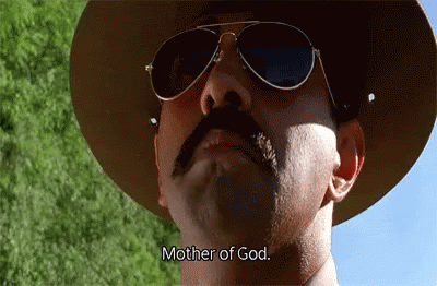 A Man With A Mustache Wearing A Hat And Sunglasses Says Mother Of God GIF