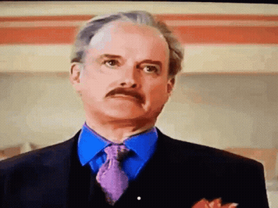 A Man With A Mustache Wearing A Suit And Tie Looks At The Camera GIF