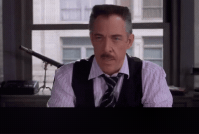 A Man With A Mustache Wearing A Vest And Tie Looks At The Camera GIF