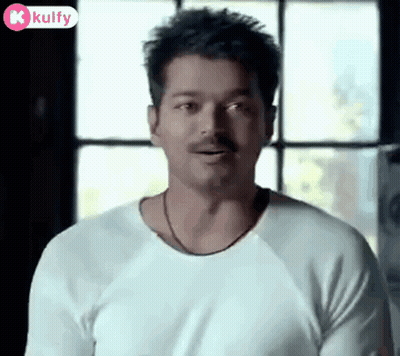 A Man With A Mustache Wearing A White Shirt Is Standing In Front Of A Window . GIF