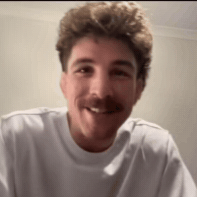 A Man With A Mustache Wearing A White Shirt Smiles For The Camera GIF