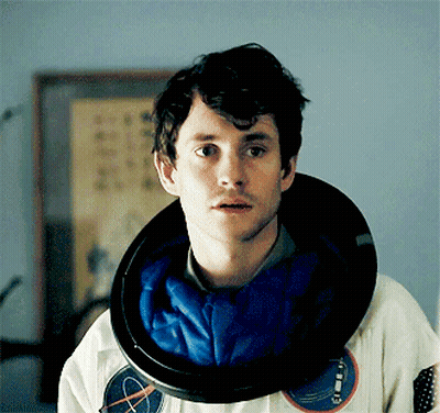 A Man With A Nasa Helmet Around His Neck Looks At The Camera GIF