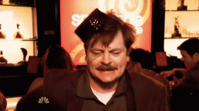 A Man With A Nbc Logo On His Shirt Is Sitting At A Table GIF