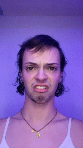 A Man With A Necklace Around His Neck Is Making A Face GIF