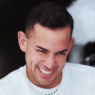 A Man With A Pearl Necklace Around His Neck Smiles For The Camera GIF