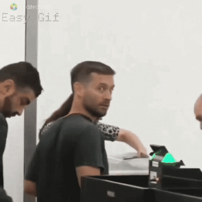 A Man With A Ponytail Is Standing Next To A Woman At A Counter . GIF