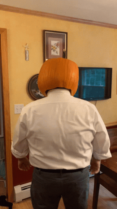A Man With A Pumpkin On His Head In Front Of A Tv GIF