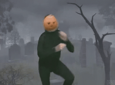 A Man With A Pumpkin On His Head Is Standing In A Cemetery . GIF