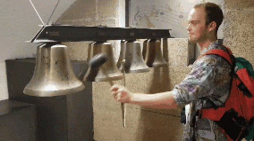 A Man With A Red Backpack Playing A Bell GIF