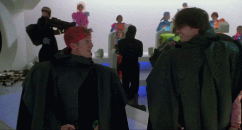 A Man With A Red Headband Is Standing Next To Another Man GIF