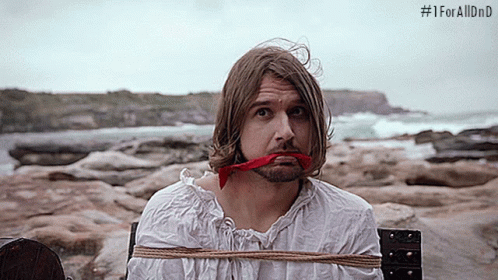 A Man With A Red Ribbon In His Mouth Is Tied To A Wooden Post With # 1Foralldnd Written On The Bottom GIF