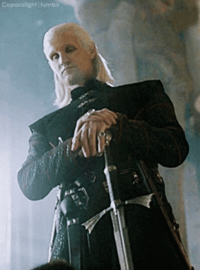 A Man With A Ring On His Finger Is Holding A Sword In His Hand GIF