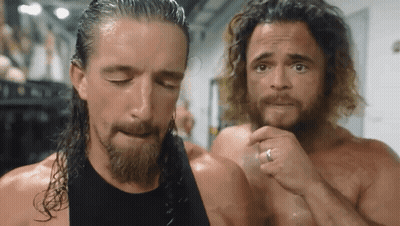 A Man With A Ring On His Finger Is Standing Next To Another Man With Long Hair GIF