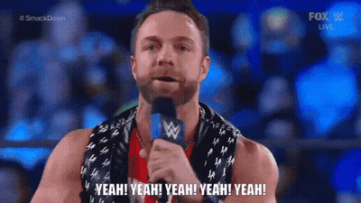 A Man With A Scarf Around His Neck Is Holding A Microphone And Saying Yeah Yeah Yeah Yeah Yeah GIF