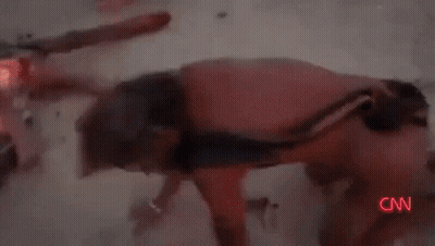 A Man With A Scarf Around His Neck Is Standing In The Desert . GIF