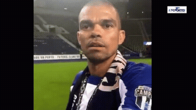 A Man With A Scarf Around His Neck Is Wearing A Blue And White Shirt With The Number 14 On It . GIF
