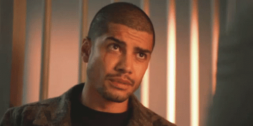 A Man With A Shaved Head And A Beard Is Looking Up At The Camera . GIF