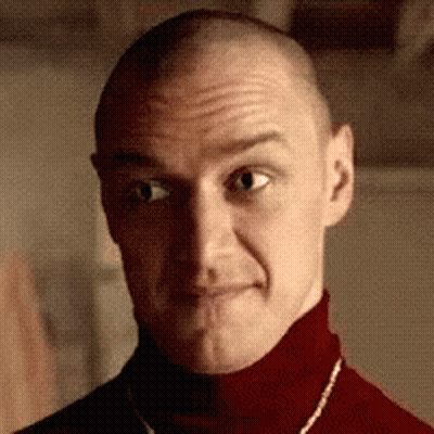 A Man With A Shaved Head Is Wearing A Red Turtleneck And A Necklace . GIF