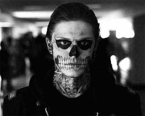 A Man With A Skull Painted On His Face And A Tattoo On His Neck Is In A Black And White Photo . GIF