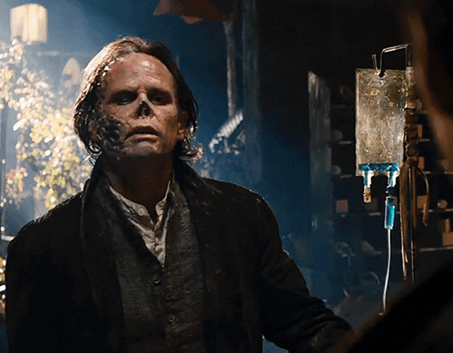 A Man With A Skull Painted On His Face Stands In Front Of A Drip GIF