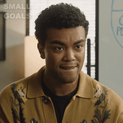 A Man With A Small Achievable Goals Sign In The Background GIF