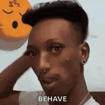 A Man With A Smiley Face On His Head Is Holding His Hand To His Forehead . GIF