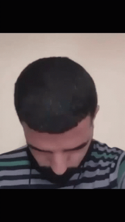 A Man With A Striped Shirt And A Beard Is Looking Down GIF