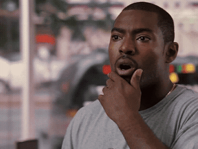 A Man With A Surprised Look On His Face Holds His Hand To His Chin GIF