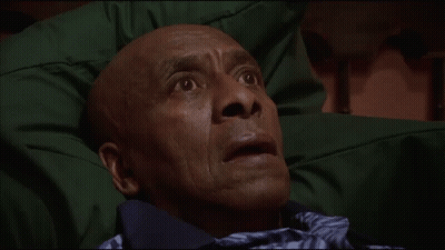 A Man With A Surprised Look On His Face Is Laying On A Green Blanket GIF
