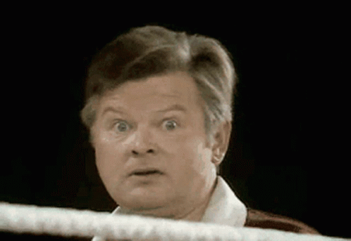A Man With A Surprised Look On His Face Is Looking Over A Rope In A Boxing Ring . GIF