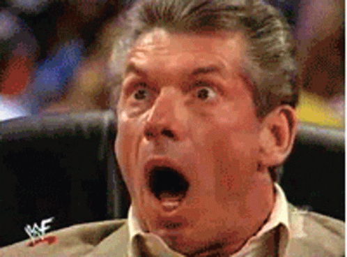 A Man With A Surprised Look On His Face Is Sitting In A Chair With A Wrestlemania Logo On His Shirt GIF