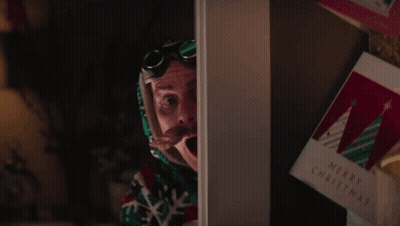 A Man With A Surprised Look On His Face Is Standing In Front Of A Christmas Card GIF