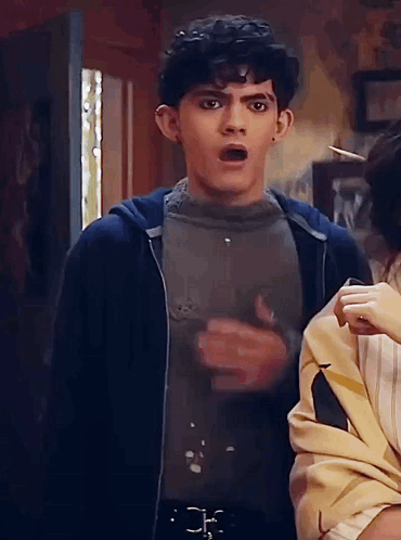 A Man With A Surprised Look On His Face Is Standing Next To A Woman In A Room . GIF