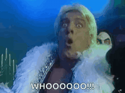 A Man With A Surprised Look On His Face Is Wearing A White Fur Coat And A White Feather Boa . GIF