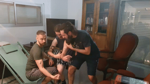 A Man With A Tattoo On His Arm Holds Another Man GIF