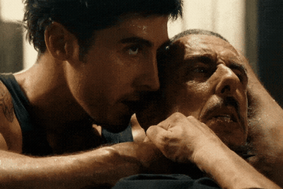 A Man With A Tattoo On His Arm Holds Another Man 'S Head GIF
