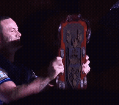 A Man With A Tattoo On His Arm Holds Up A Plaque That Says World State Of Origin GIF