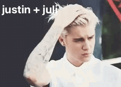 A Man With A Tattoo On His Arm Is Holding His Hair . GIF