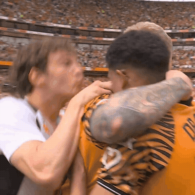 A Man With A Tattoo On His Arm Is Hugging Another Man With A Tiger Print Shirt GIF