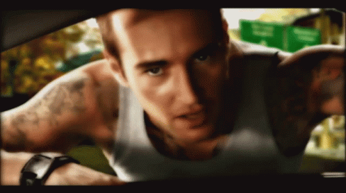 A Man With A Tattoo On His Arm Is Looking At The Camera GIF