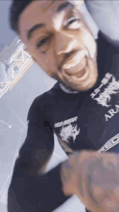 A Man With A Tattoo On His Arm Is Making A Funny Face While Wearing A Black Shirt . GIF