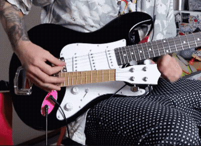 A Man With A Tattoo On His Arm Is Playing An Electric Guitar GIF