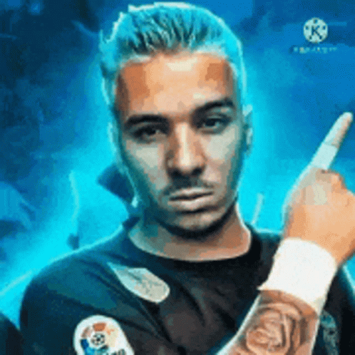 A Man With A Tattoo On His Arm Is Pointing At The Camera With His Finger . GIF