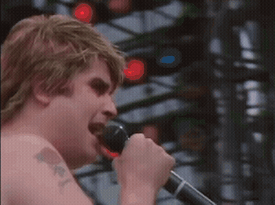 A Man With A Tattoo On His Arm Is Singing Into A Microphone .. GIF