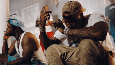 A Man With A Tattoo On His Arm Is Sitting Next To Another Man GIF