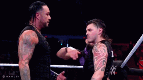 A Man With A Tattoo On His Arm Is Standing In A Ring With Two Other Men GIF