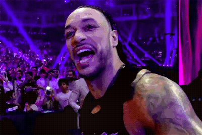 a man with a tattoo on his arm is standing in front of a crowd and smiling .