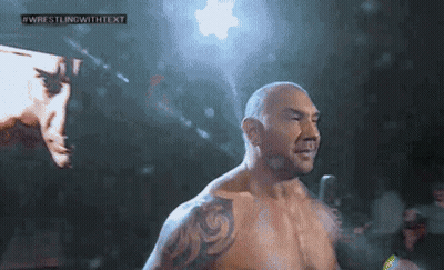 A Man With A Tattoo On His Arm Is Standing In Front Of A Screen That Says Wrestling With Text GIF
