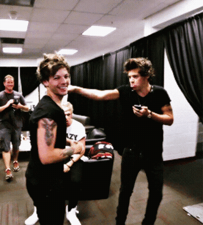 A Man With A Tattoo On His Arm Is Standing Next To Another Man Who Is Holding A Cell Phone GIF